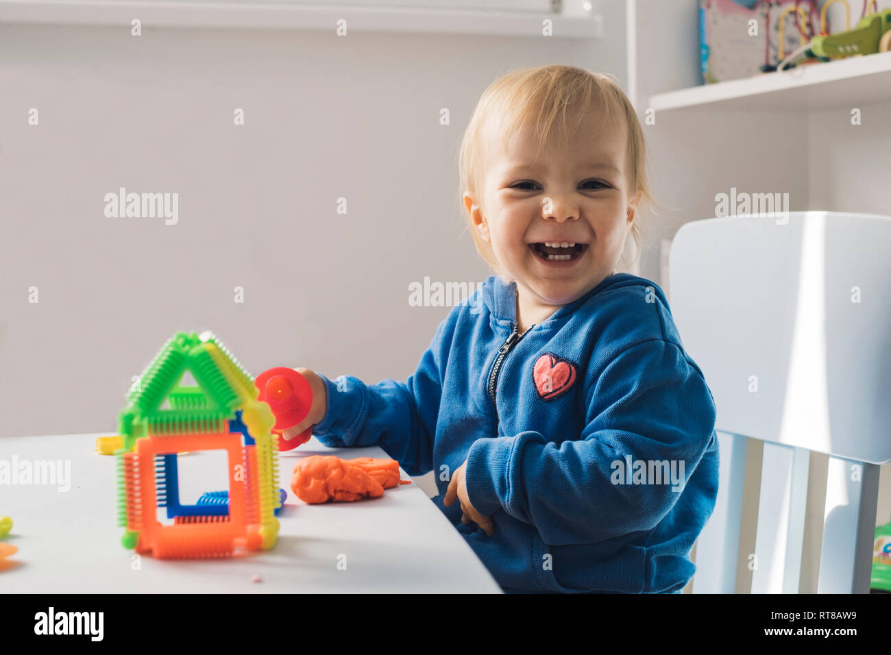 Portrait von lachendes Baby Mädchen spielen mit Knetmasse Stockfoto