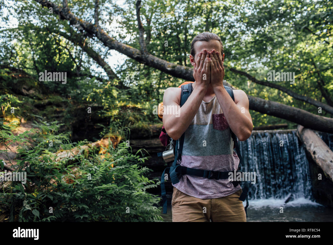 Junger Mann mit Rucksack erfrischende an Wasser in einem Wald Stockfoto