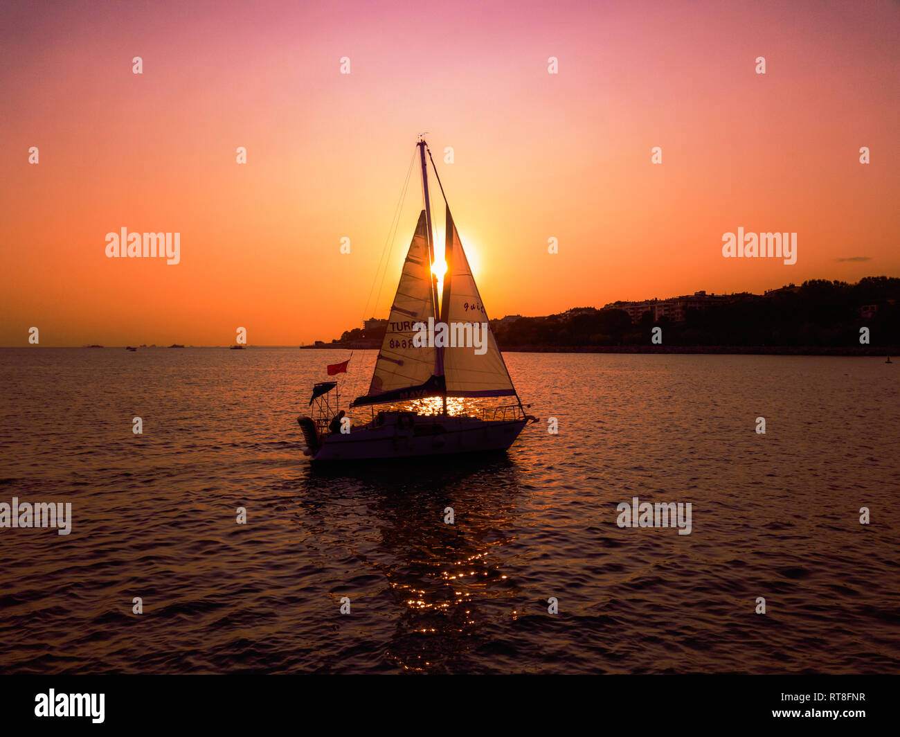 Segelboot durch den Sonnenuntergang. Sun können zwischen Segel gesehen werden. Stockfoto