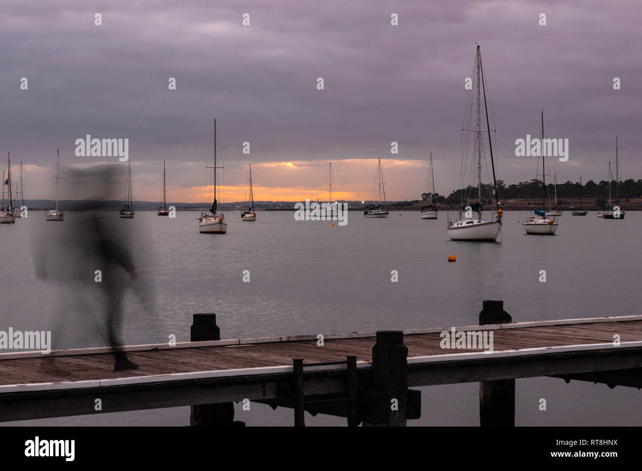 Person in Bewegung entlang Pier bei Sonnenaufgang Stockfoto