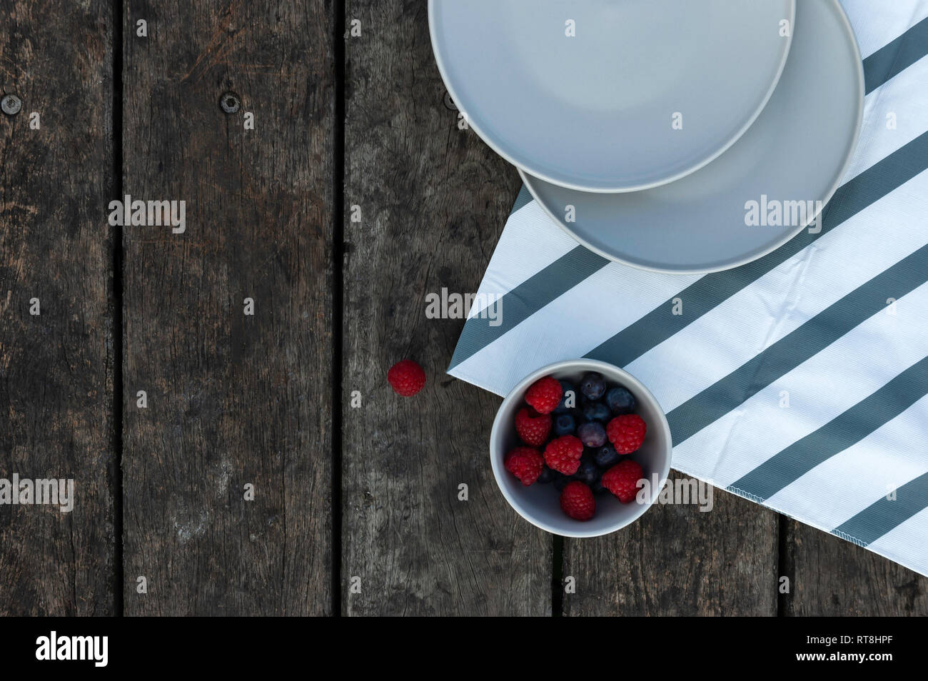 Flach, Beeren im minimalistischen Schüssel mit Holzbohlen Stockfoto