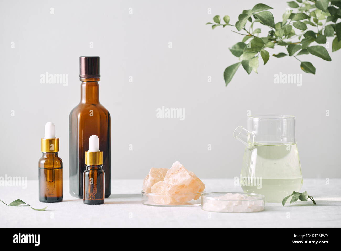 Aromatherapie. Kleine Glasflaschen mit kosmetischen Öle. Badesalz. Frische Blätter. Objekte für Prozeduren auf weißem Hintergrund Blatt. Stockfoto