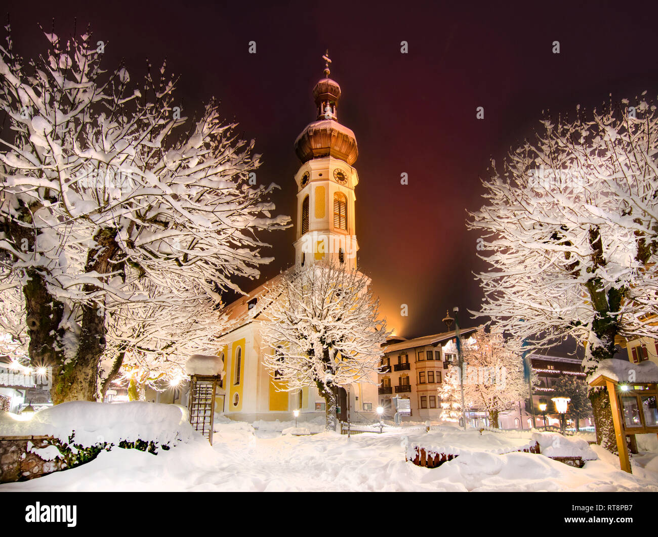 Gelbe Kirche in Bergdorf auf Weihnachten im verschneiten Winterlandschaft reisen Bayern Reit im Winkl Stockfoto