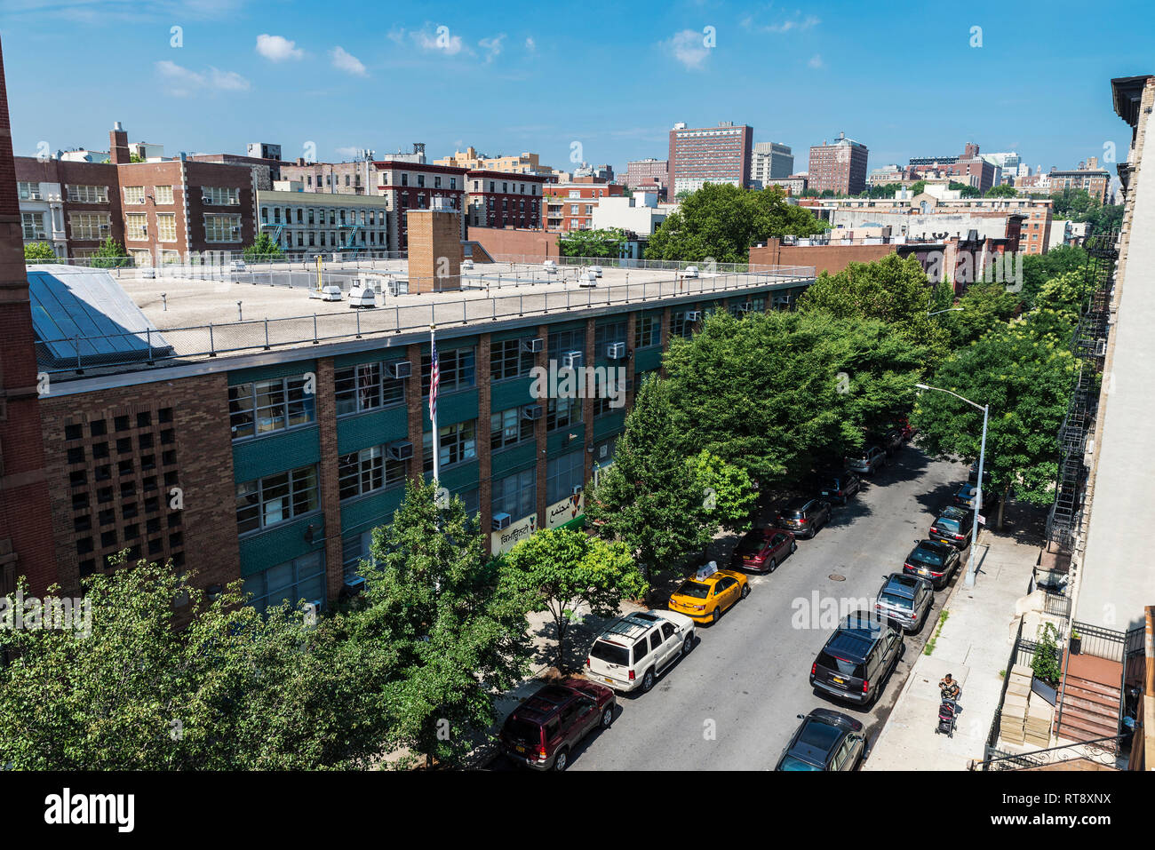 New York City, USA - 28. Juli 2018: Überblick über eine Straße mit ihren alten typischen Häuser und Menschen um im Harlem Stadtteil von Manhattan, New Yo Stockfoto