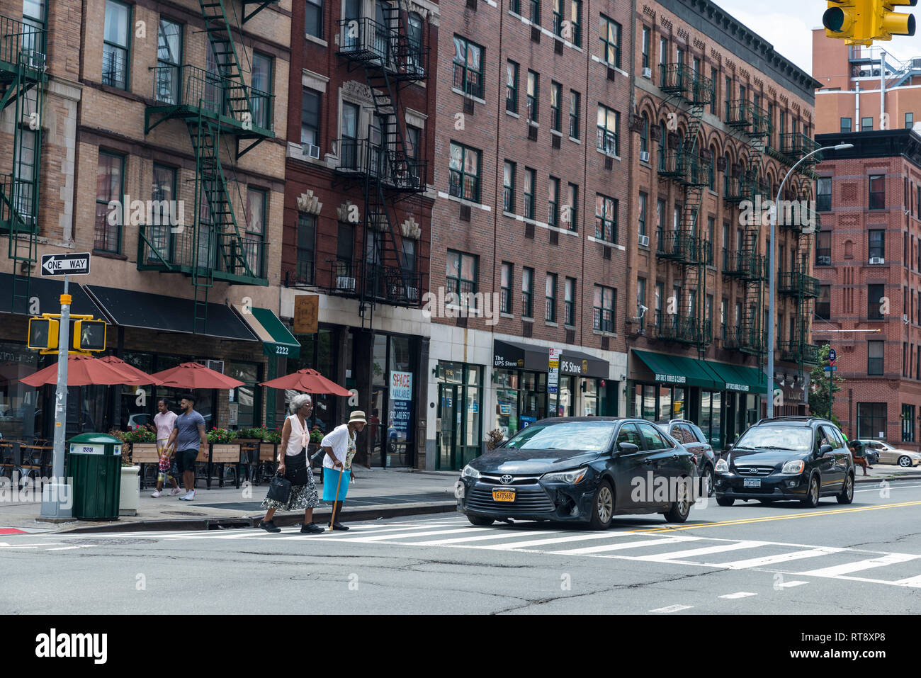 New York City, USA - 28. Juli 2018: Zwei alte schwarze Frauen mit einem Spazierstock Kreuzung eine Ampel, Zebrastreifen in Harlem, Manhattan, New York City Stockfoto