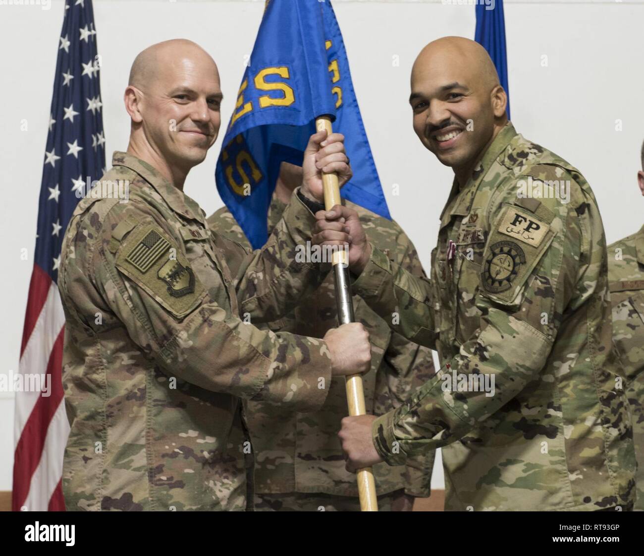 Maj. Shane Patty (rechts) übergibt das Kommando über die 407. Expeditionary Bauingenieur Squadron durch Übergeben des Guidon zu oberst Scott Gibson (links), 407 Air Expeditionary Gruppenkommandant, während der 407 ECES Ändern des Befehls Zeremonie an einem geheimen Ort im Südwesten Asien Jan. 25, 2019. Die Verabschiedung des Guidon ist eine symbolische Geste in der militärischen Tradition, was bedeutet, dass die Übertragung der Befehls Behörde von einem Führer zum nächsten. Stockfoto