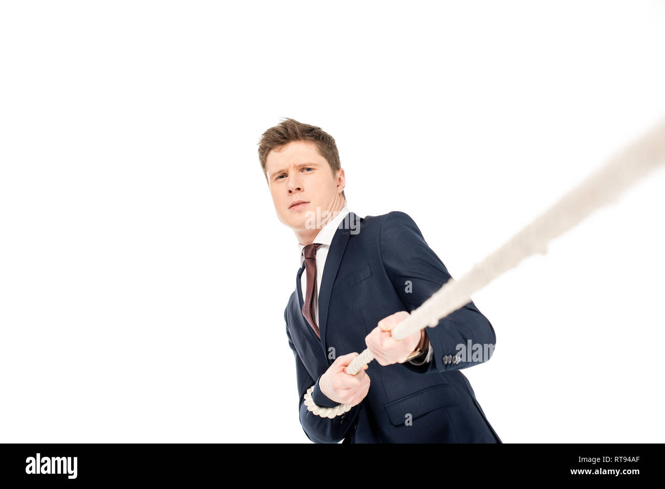 Hübscher junger Geschäftsmann ziehen Seil isoliert auf weißem Stockfoto