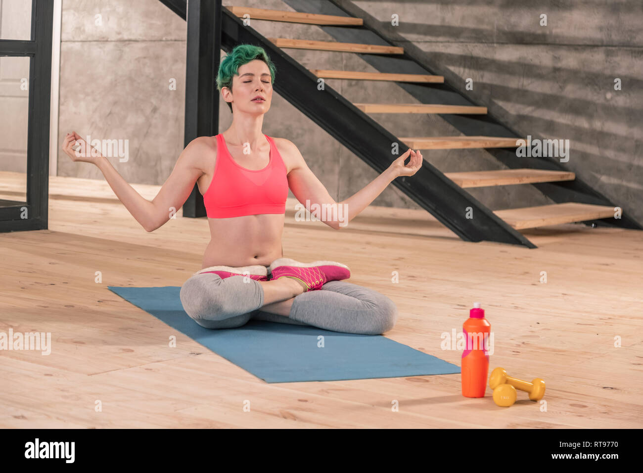 Grün - behaarte Frau Meditation sitzend auf blaue Sport mat Stockfoto