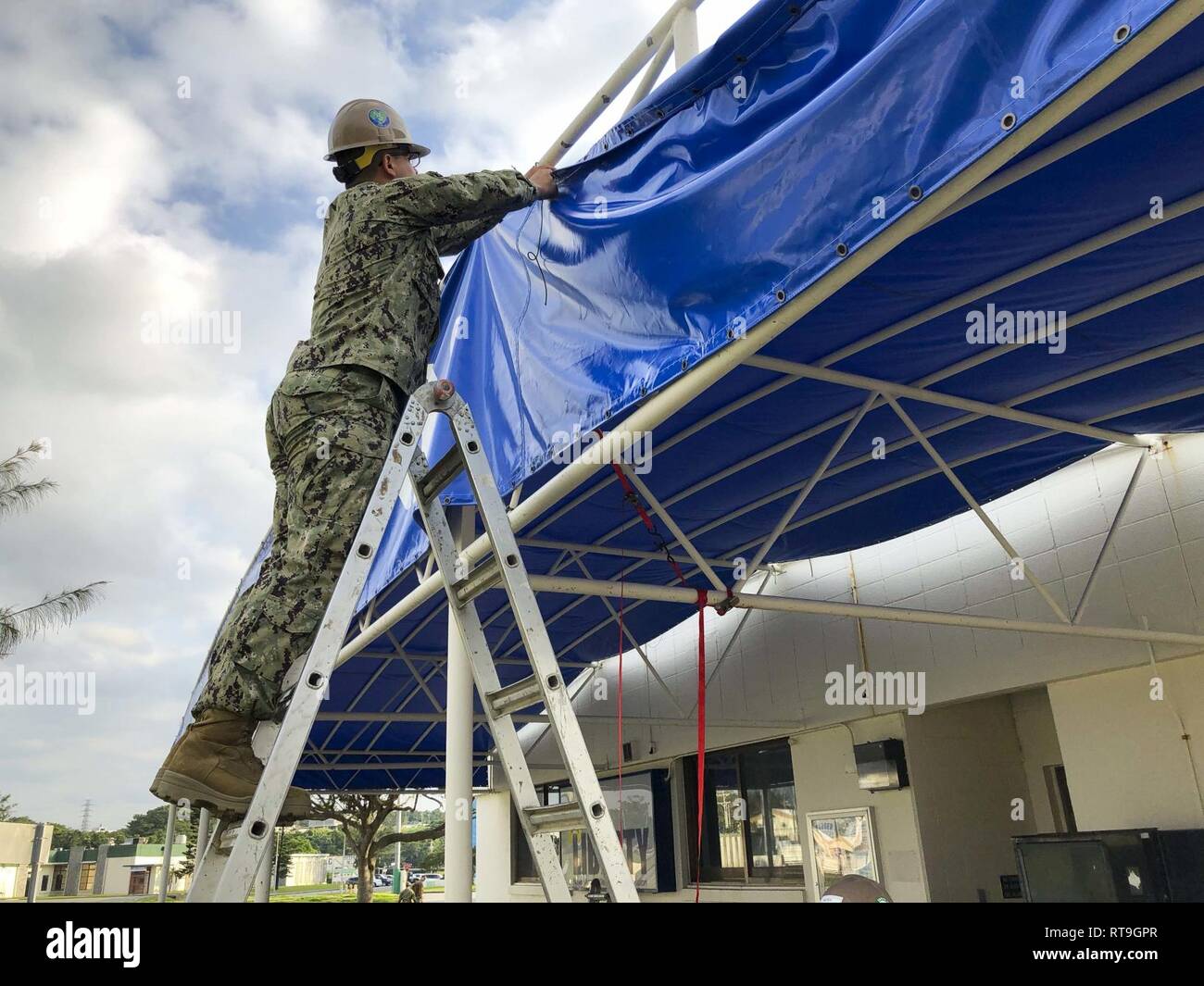 OKINAWA, Japan (Jan. 29, 2019) Bau Utilitiesman rekrutieren Brendan Murray, zu Naval Mobile Konstruktion Bataillon (NMCB) 3, errichtet eine Seabee - themed Markise außerhalb des Liberty Center onboard Camp Schilde in Okinawa, Japan zugeordnet. NMCB-3 ist uns in der gesamten indopazifischen Region und die Vereinigten Staaten bereit, größeren Kampfhandlungen zu unterstützen, Theater Sicherheit, humanitäre Hilfe und Katastrophenhilfe im Einsatz. Stockfoto