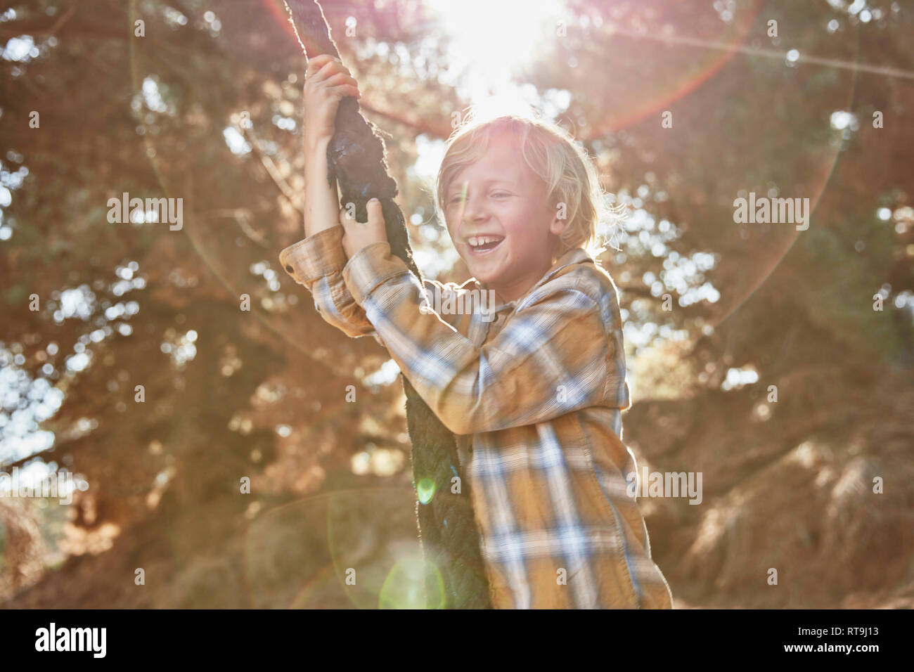 Happy Boy Schwingen am Seil in der Hintergrundbeleuchtung Stockfoto