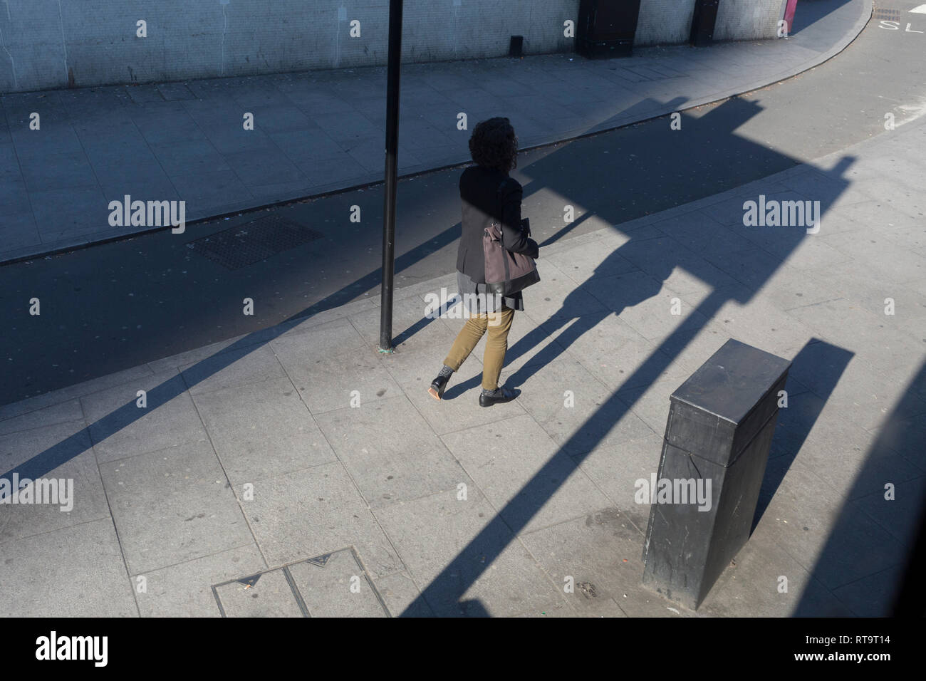 Eine Dame geht in den Schatten eines Verkehr Wegweiser im Elephant & Castle in Southwark, am 25. Februar 2019 in London, England. Stockfoto