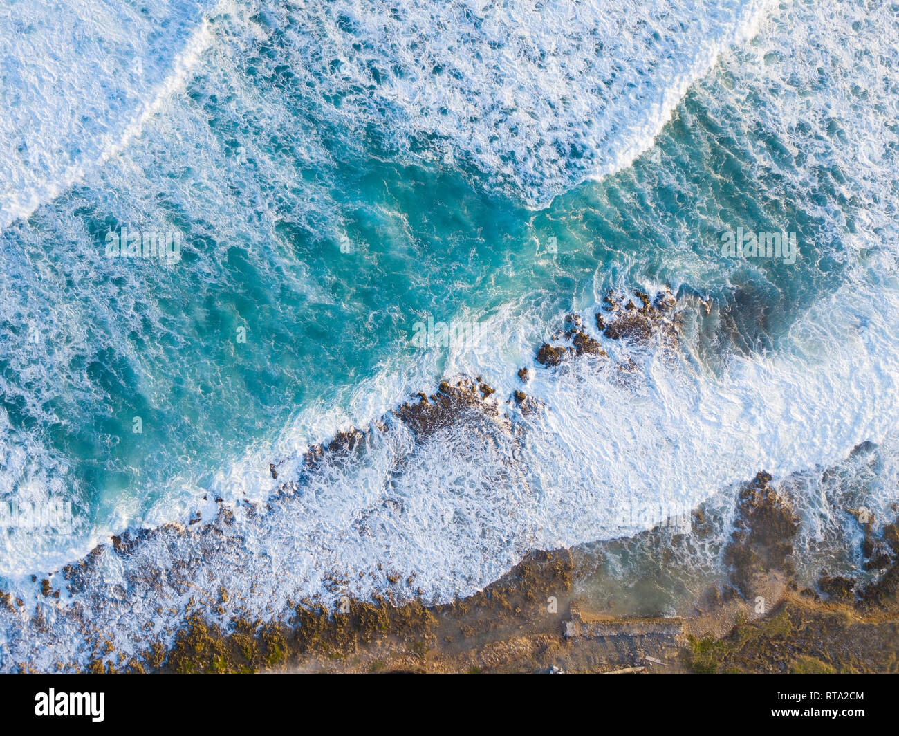Antenne Drone geschossen, der Ozean und die Welle bricht auf der felsigen Küste von oben. Stockfoto