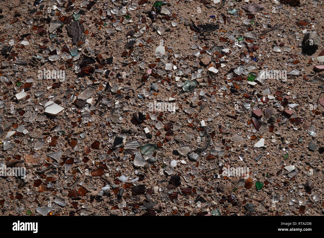 Ein Haufen Glasscherben von mehreren Flaschen auf dem Sand in der Wüste. Stockfoto