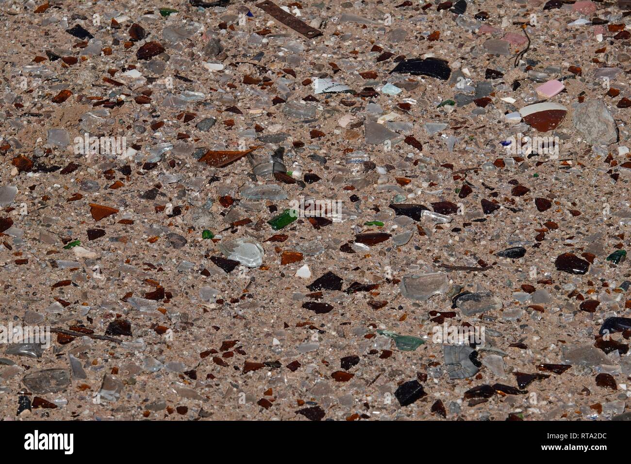Ein Haufen Glasscherben von mehreren Flaschen auf dem Sand in der Wüste. Stockfoto