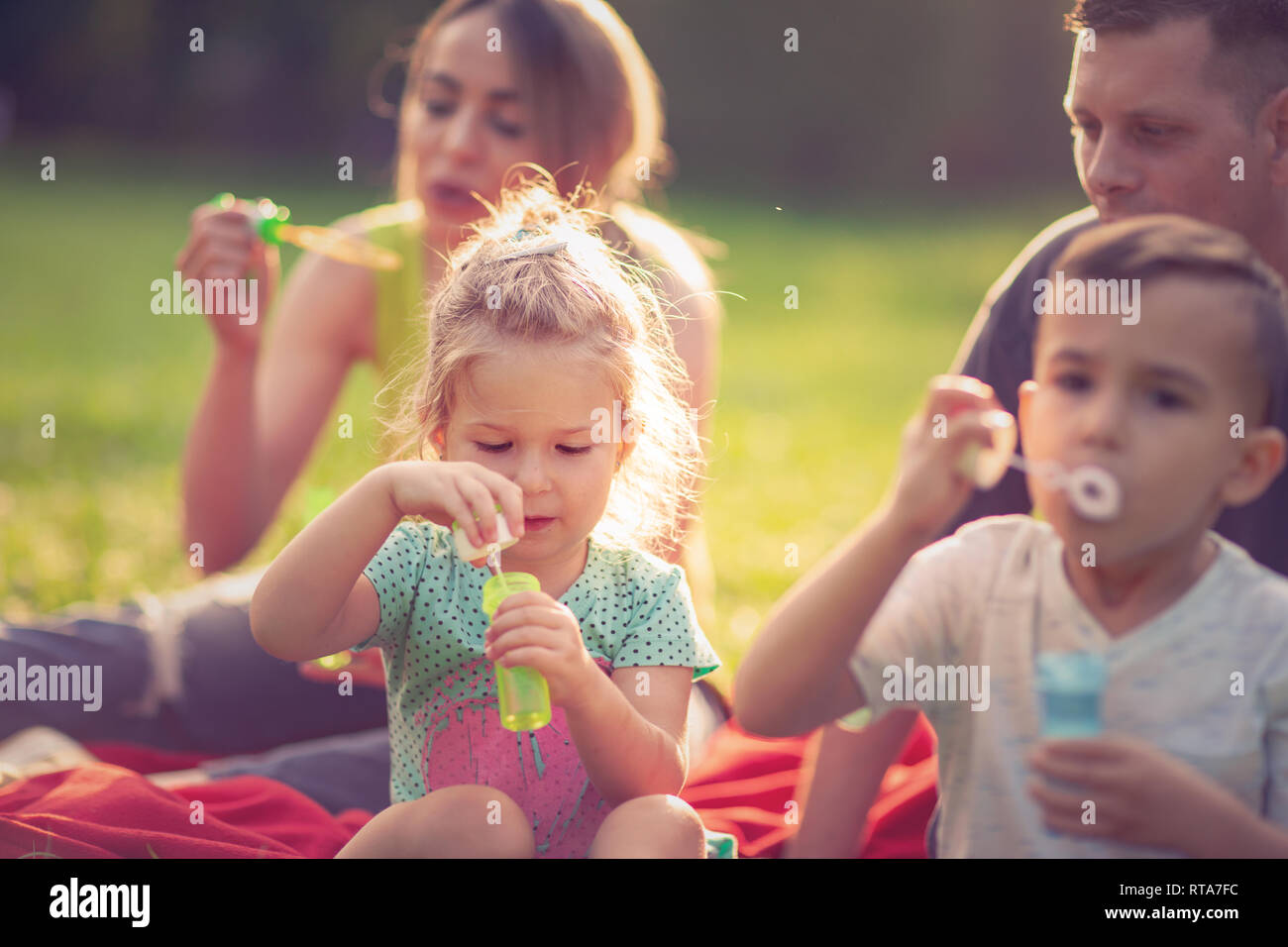 Süße Mädchen bläst Seifenblasen mit ihrer Familie im Park Stockfoto