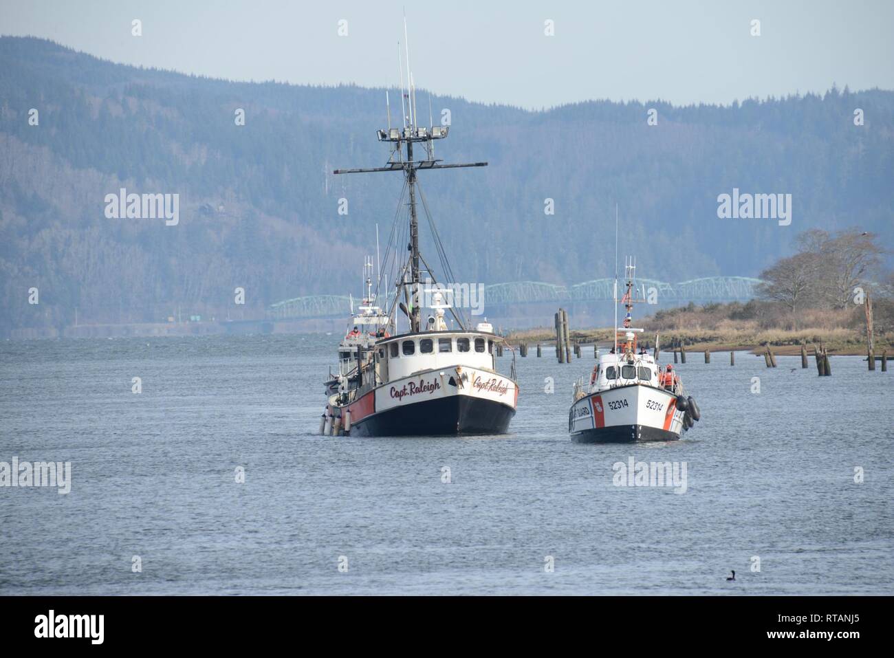 Die Crew der 52-Fuß-Motor Life Boat Triumph II, von der Coast Guard Station Cape Enttäuschung, betritt die Skipanon Marina in Warrenton, Erz, während die kommerzielle Fischerei Schiff Kapitän Raleigh, Feb 7, 2019 abschleppen. Die 52-Fuß-MLB hat den besten Anhängelast und Übertragungsbereich aller aktiven Küstenwache kleine Boote. Us-Küstenwache Stockfoto