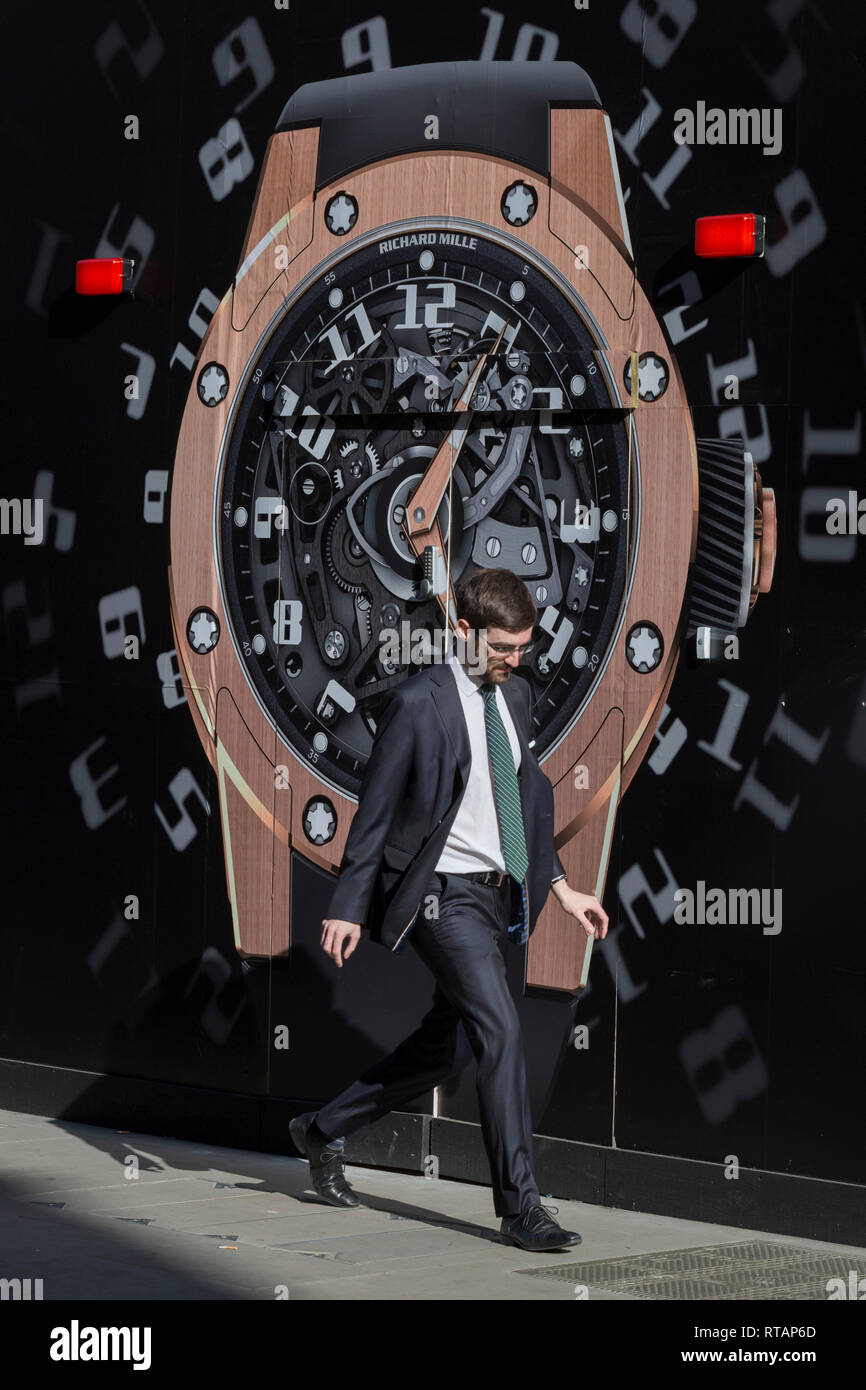 Ein Geschäftsmann Wanderungen vorbei an einem Bau das Horten von einer Uhr außerhalb der neuen Richard Mille shop in New Bond Street, am 25. Februar 2019 in London, England. Stockfoto