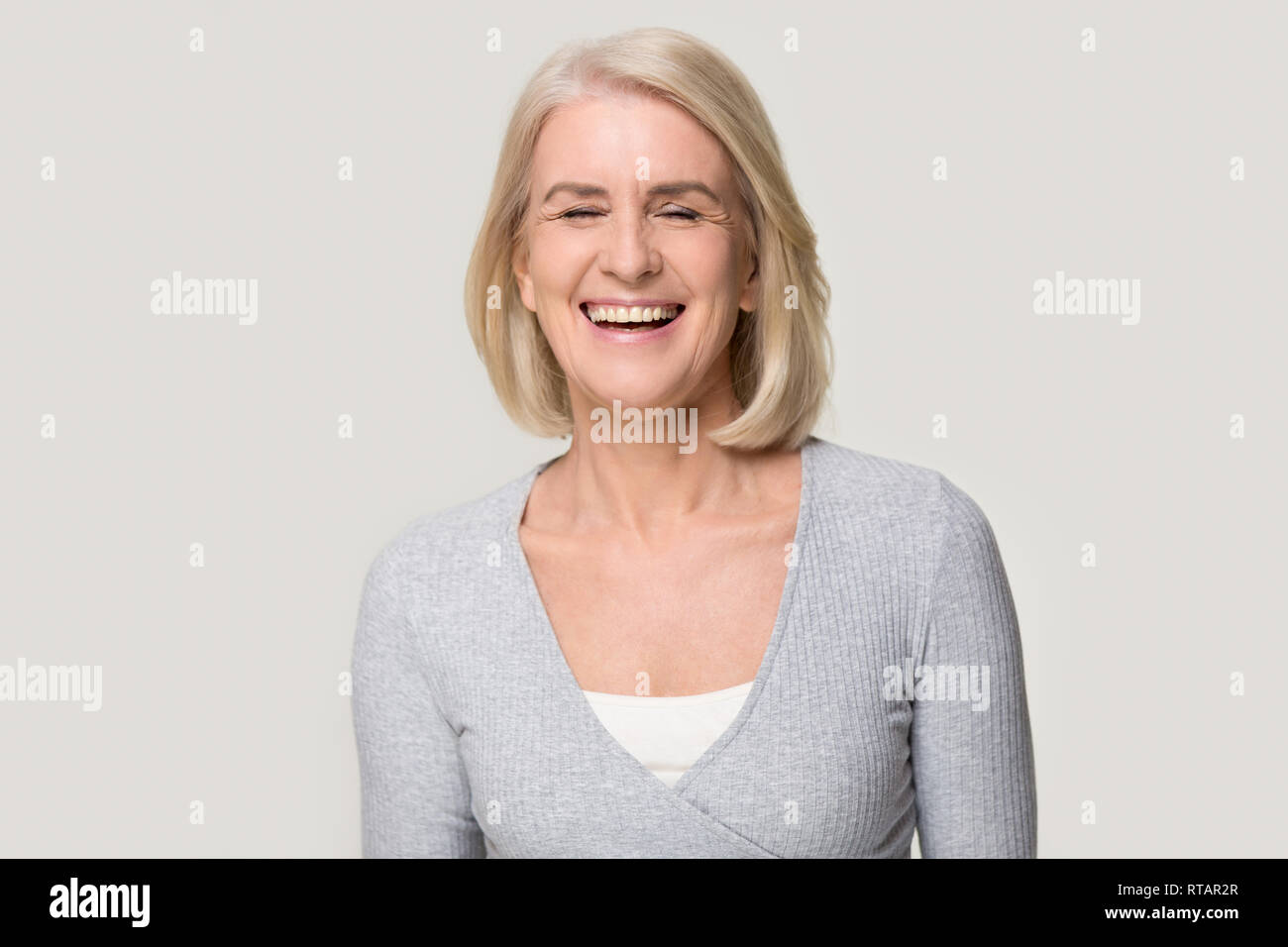 Gerne Mitte der gealterte Frau auf Grau studio Hintergrund lachen Stockfoto