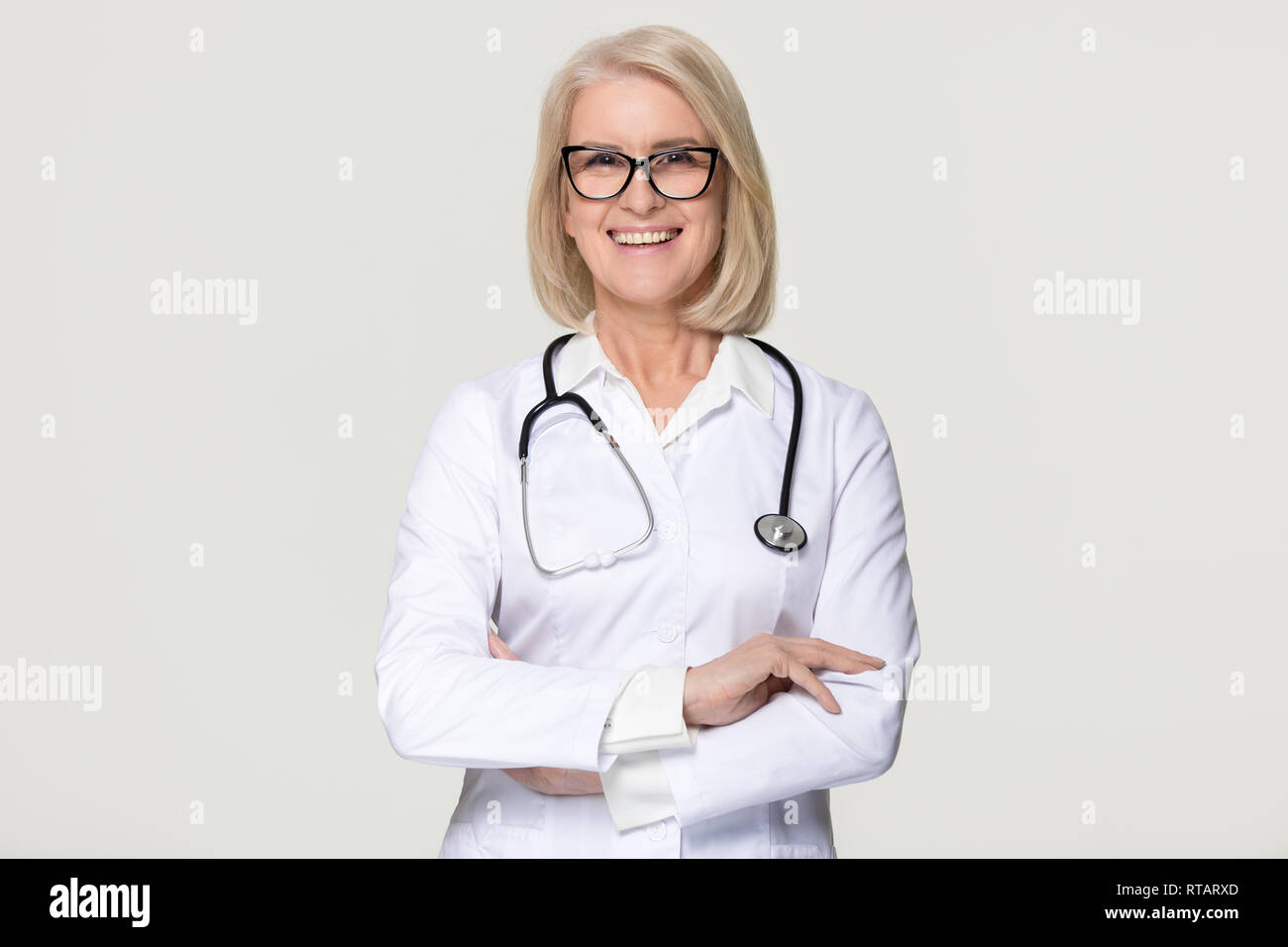 Gerne reife Frau Doktor Portrait auf grauem Hintergrund Stockfoto