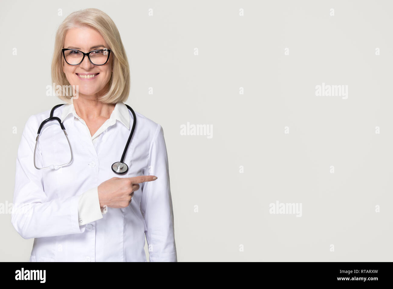 Lächelnd Arzt mit Stethoskop an Copyspace auf Hintergrund zeigen Stockfoto