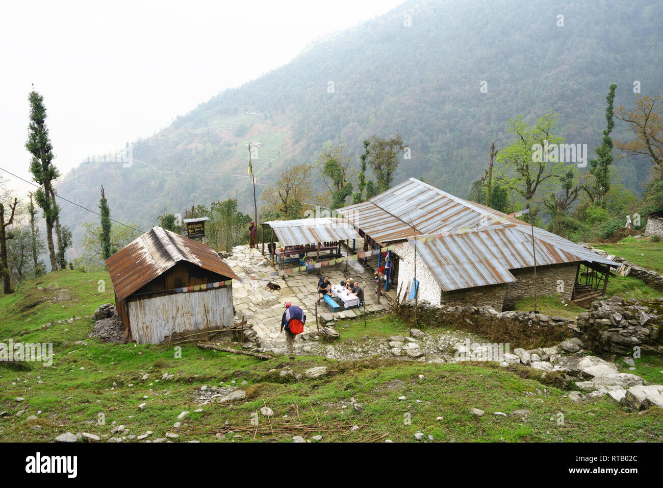 Porter in einer Pension, wo Wanderer eine Pause ankommen, an einem Tisch sitzen. Annapurna Conservation Area, Nepal. Stockfoto Porter in einer Pension, wo Wanderer eine Pause ankommen, an einem Tisch sitzen. Annapurna Conservation Area, Nepal. Stockfoto