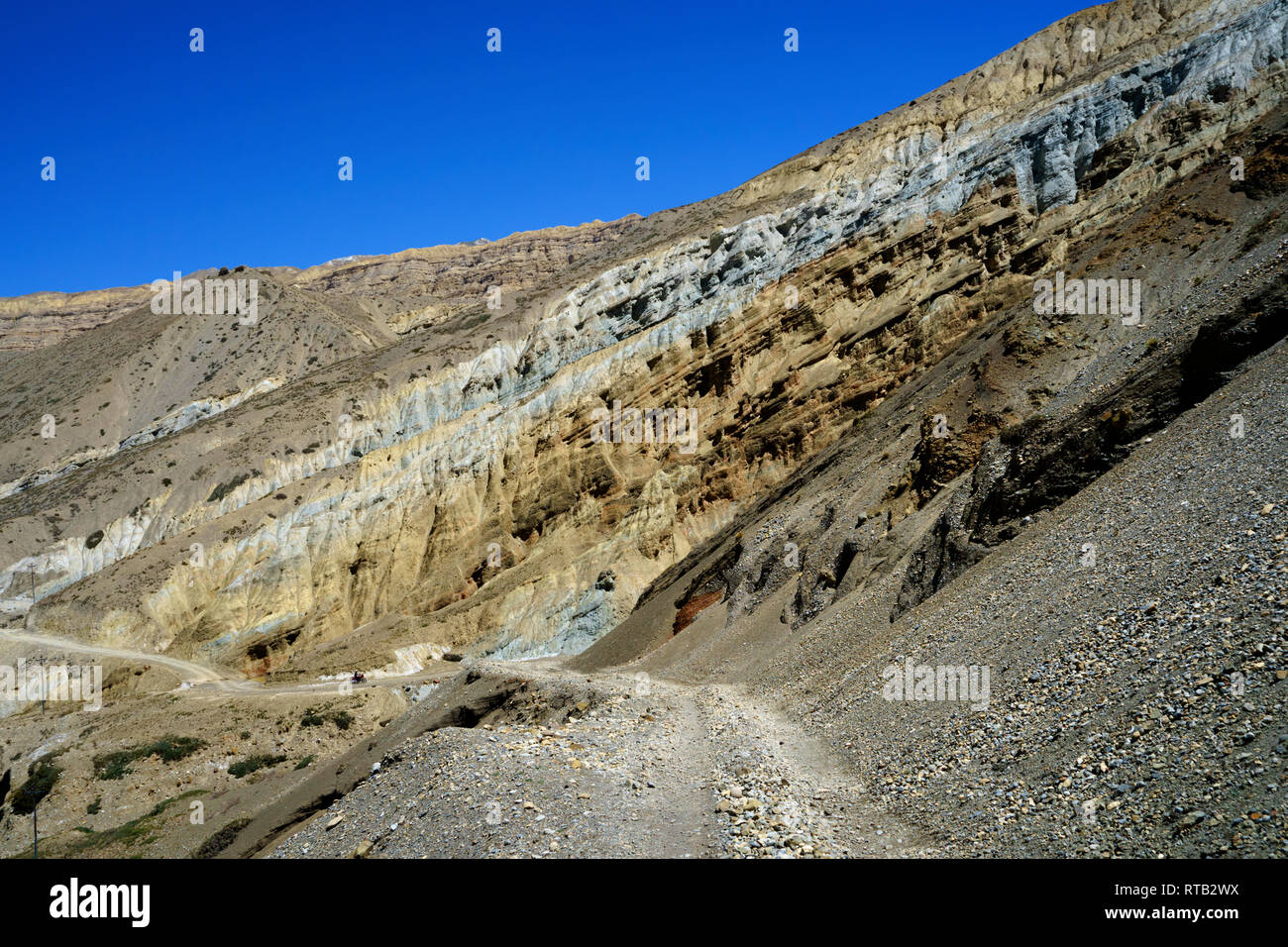 Ein Motorrad und seinen Reiter werden von den gigantischen Klippen in der Nähe von Chuksang, Upper Mustang, Nepal in den Schatten gestellt. Stockfoto