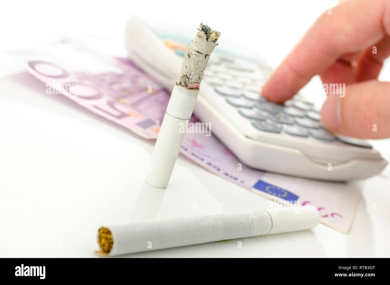 Die Hälfte verbrannt Zigarette mit Taschenrechner und Euro Geld. Konzept der großen finanziellen Belastung ist das Rauchen. Stockfoto