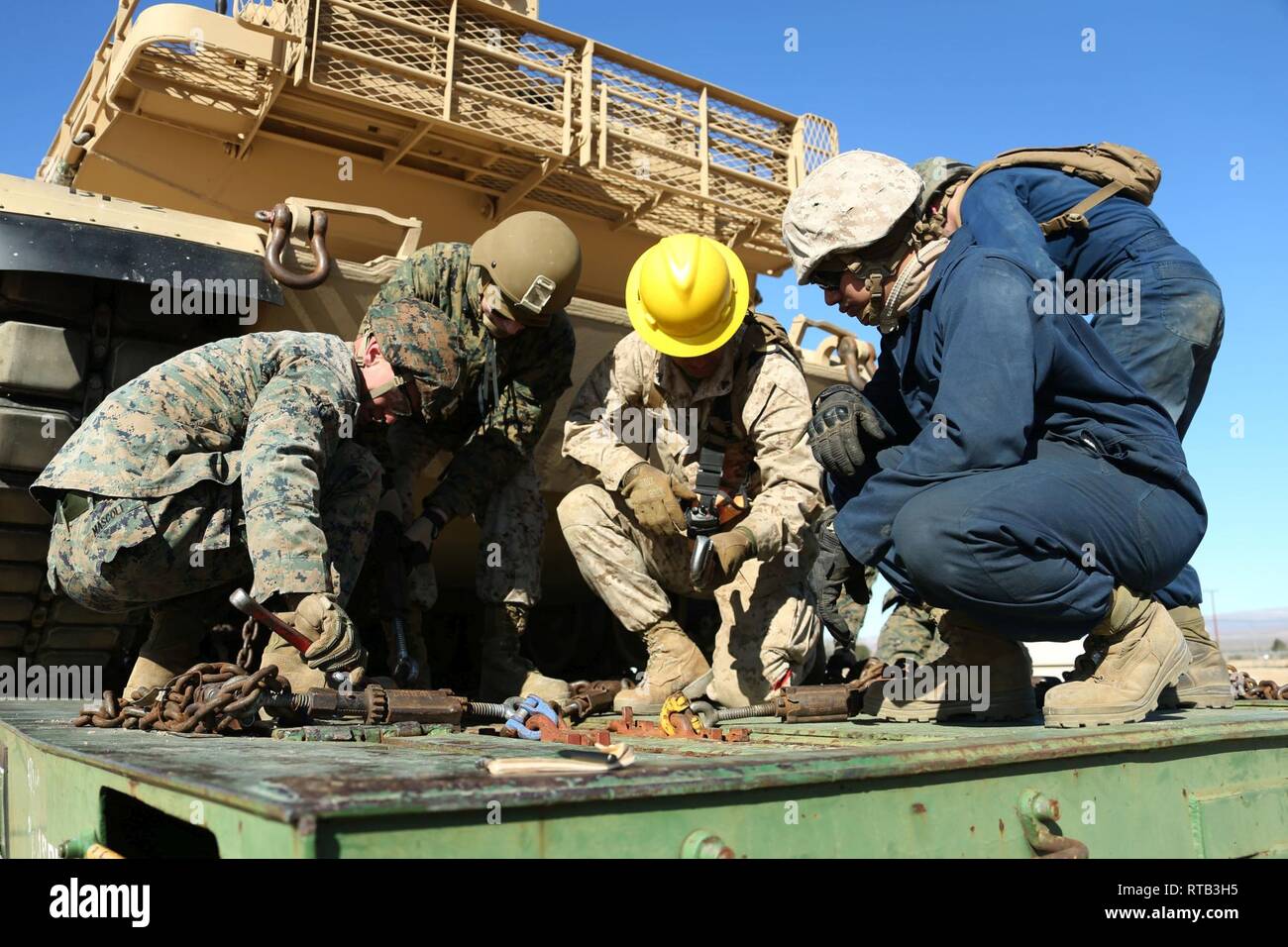 Us Marine Corps Cpl. Pablo I. De La Rosa, Mitte, mit der Bekämpfung der Logistik Bataillon 6, Bekämpfung der Logistik Regiment 2, 2 Marine Logistics Group, zeigt, wie nach unten bewegen, um die Kette zu einem M1A1 Abrams Tank während des Schienenkopfes Operationen in Vorbereitung auf die Übung Comanche beim Marine Corps Logistikstandort Barstow, Kalifornien, Feb 6, 2019. Comanche Laufen besteht aus Mobilisierung und Einschiffung Verfahren, offensive und defensive Überwachung Bewertung Mannschaften, die das Bataillon die Möglichkeit bieten, seine Bekämpfung Bereitschaft, Stabilität zu verbessern und ihre Fähigkeit zu kämpfen. Stockfoto