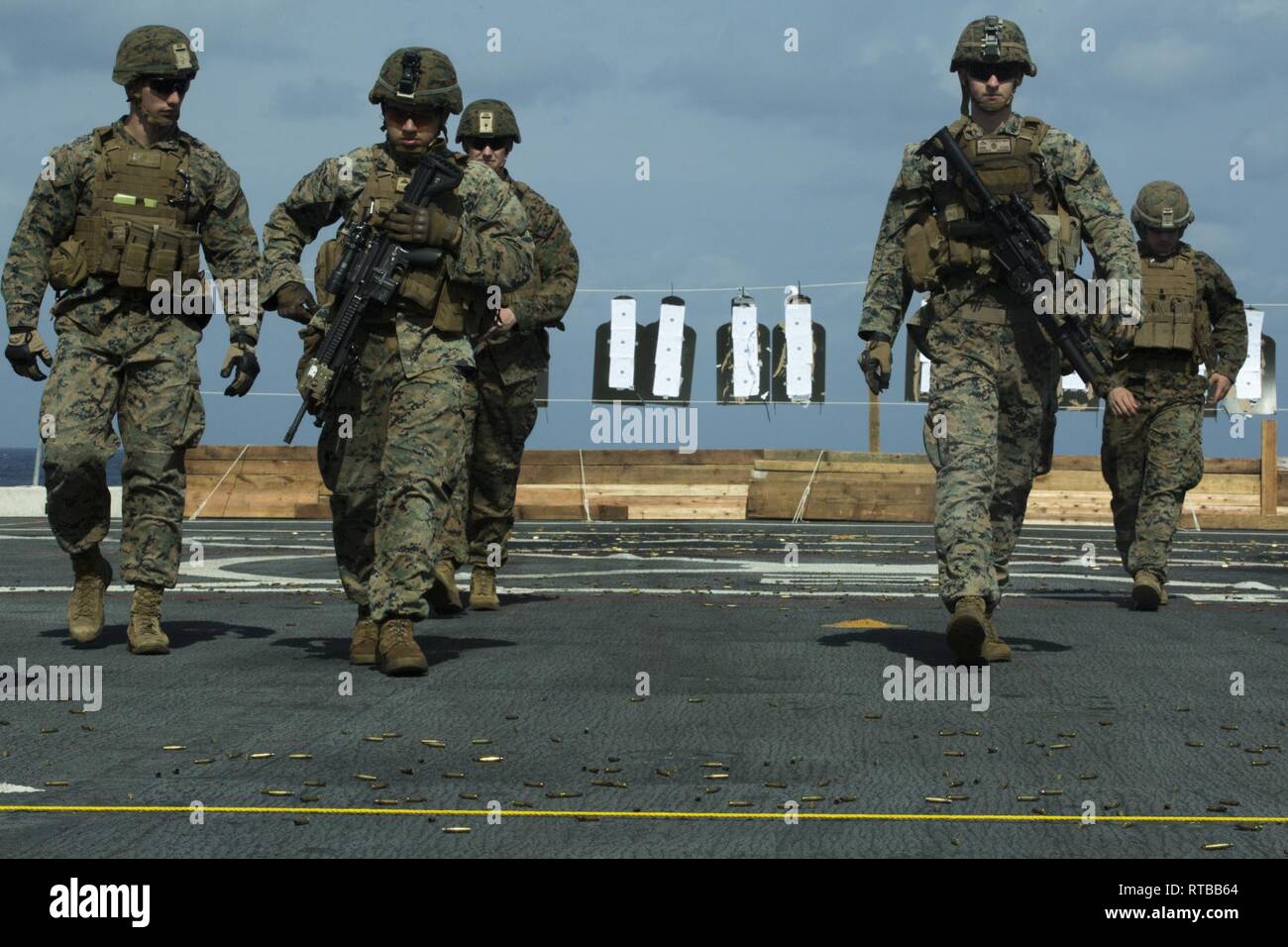 Marines mit Bravo Company, Bataillon Landung Team, 1.BATAILLON, 4 Marines, Spaziergang zurück in die Schusslinie während Treffsicherheit Training auf dem Flugdeck der USS amphibious Transport dock Green Bay LPD (20), die in der East China Sea, Feb 2, 2019. Bravo Company ist die mechanisierte raid-Unternehmen mit BLT 1/4, Bodenkampf Element für die 31 Marine Expeditionary Unit. Die 31. MEU, das Marine Corps' nur kontinuierlich vorwärts - bereitgestellt MEU partnering mit dem Wasp amphibischen bereit, Gruppe, bietet eine flexible und tödlicher Gewalt bereit, eine breite Palette von militärischen Operationen wie die Prem durchführen Stockfoto