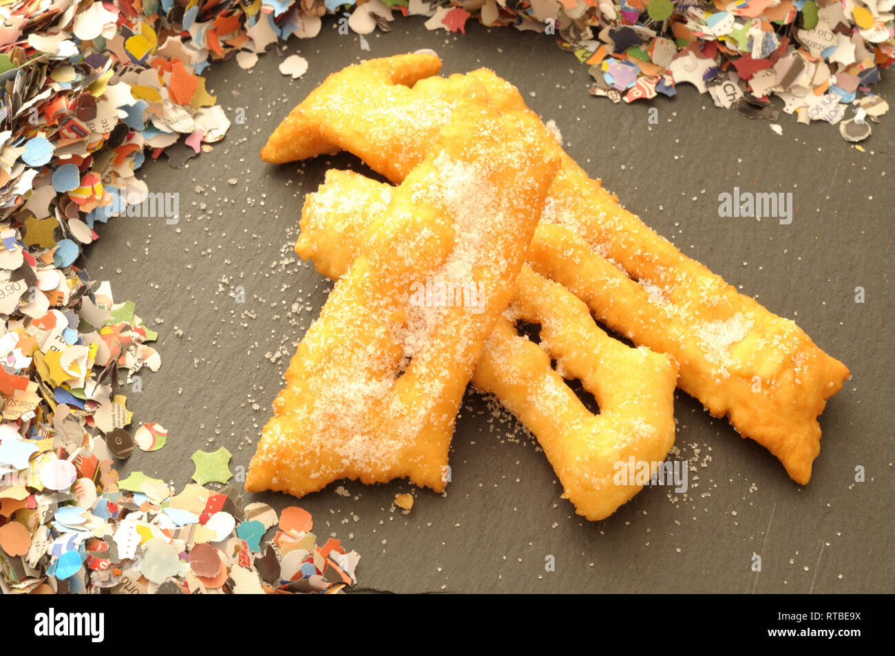 Stapel von Italienischen frittiertes Gebäck, hausgemachtes für Karneval Feier auf schiefer Platte whit farbige Konfetti Stockfoto