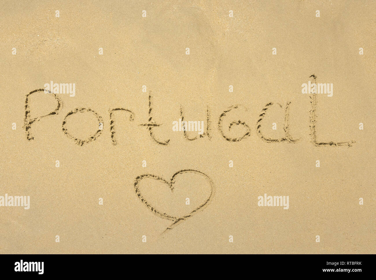 Inschrift auf nassem Sand Portuga und das Herz gemalt auf dem Sand als Symbol der Liebe. Cascais, Portugal Stockfoto