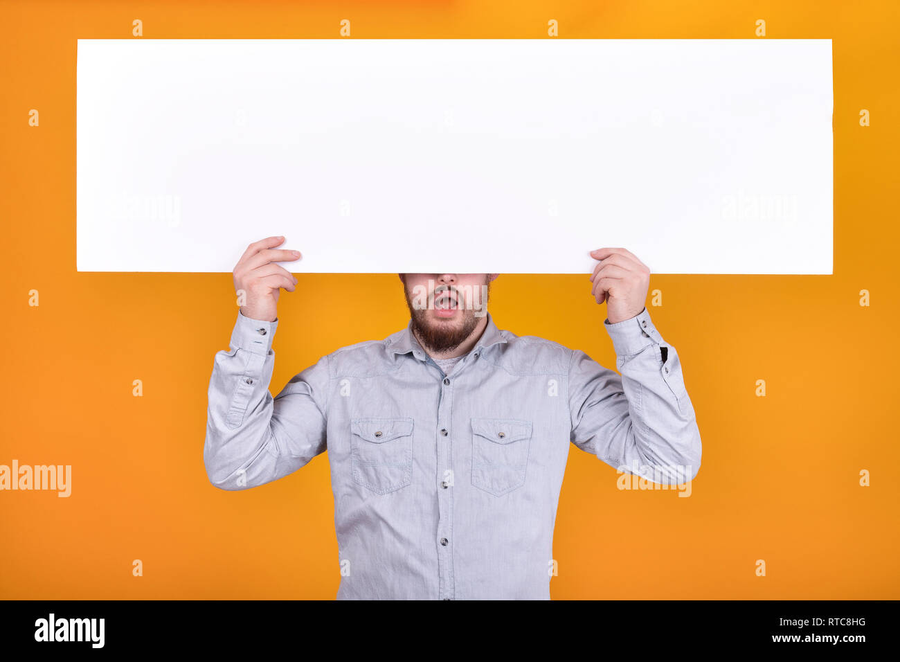 Ein Mann hält ein Plakat für Text, ausdrucksstarken Shouts und einladenden Käufer Stockfoto
