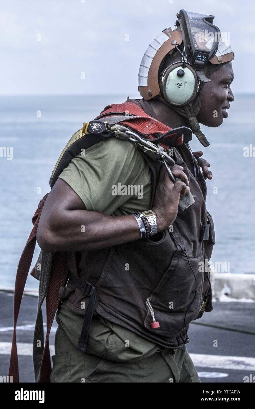 Pazifik - US Marine Cpl. Karl Tinson, ein tiltrotor Crew Chief mit Marine Medium Tiltrotor Squadron 166 verstärkt, 13 Marine Expeditionary Unit (MEU), trägt das Zahnrad an Bord der Wasp-Klasse amphibisches Schiff USS Essex (LL 2), Feb.12, 2019. Das Essex Amphibious Ready Gruppe und dem 13 MEU ist ein fähiger und tödliche Navy-Marine Corps Team in die USA 7 Flotte Bereich im Einsatz der regionalen Stabilität zu unterstützen, Partner beruhigen und Verbündeten und einer Präsenz posierten auf jede Krise, die von der humanitären Hilfe Blindbewerbungen zu reagieren pflegen. Stockfoto