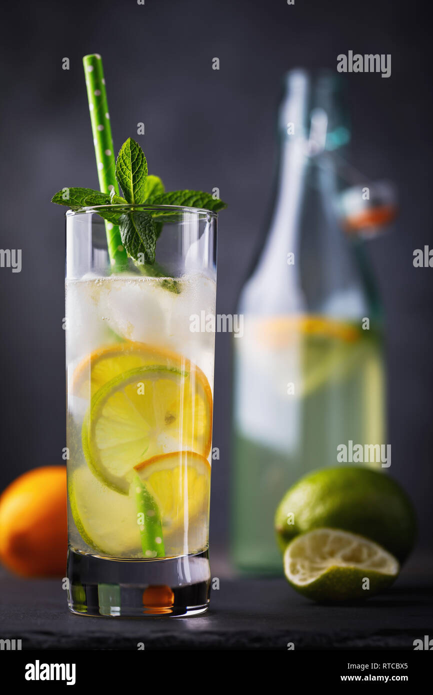 Cool Tonic mit Zitrone, Limette und Minze in ein durchsichtiges Glas mit einer offenen Flasche auf dem Tisch Stockfoto