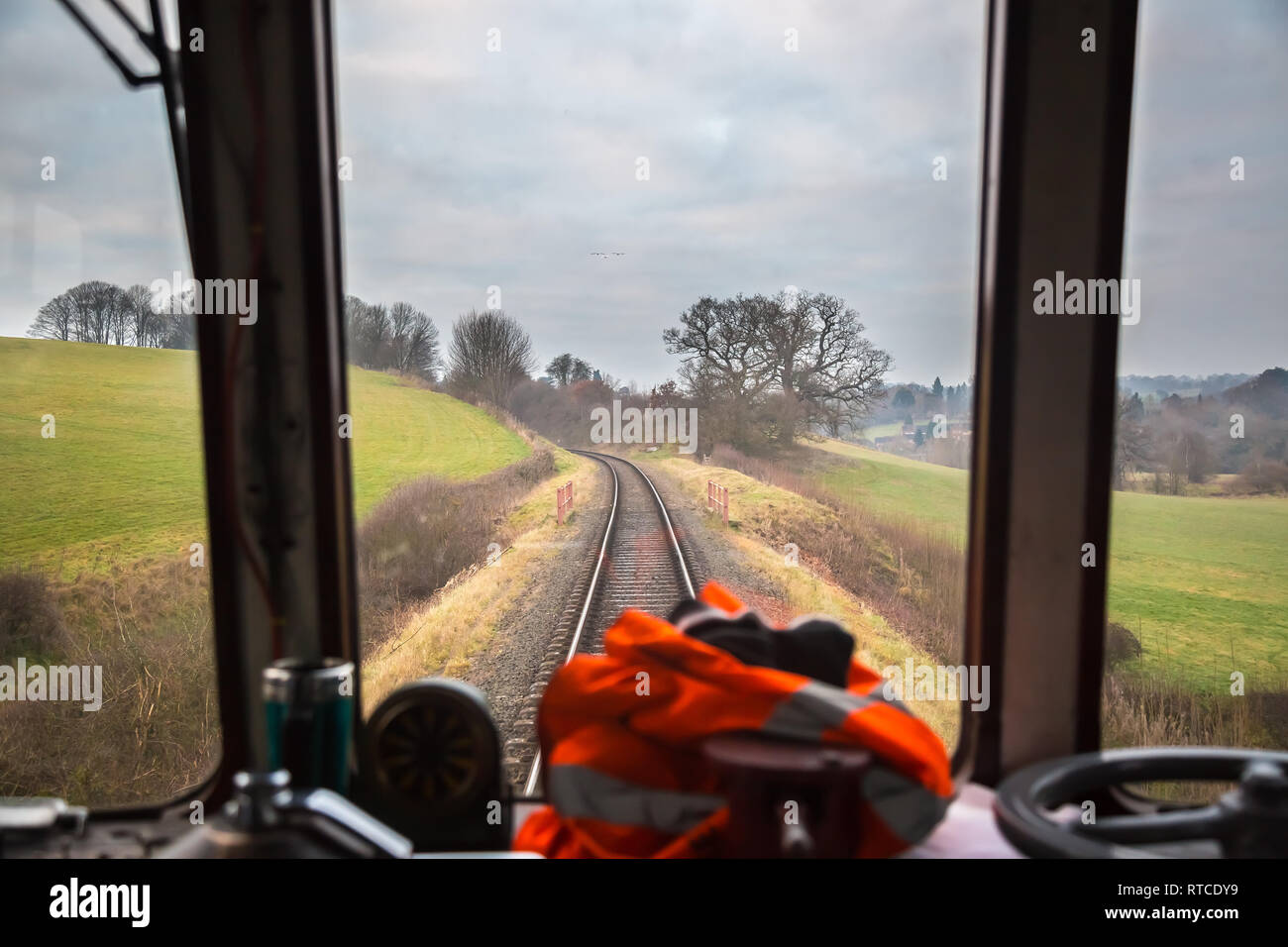 Blick auf das Cockpit des Dieseltriebfahrers durch das Kabinenfenster des fahrenden Zuges auf der historischen Linie der Severn Valley Railway, die durch die ländliche Landschaft Großbritanniens führt. Stockfoto