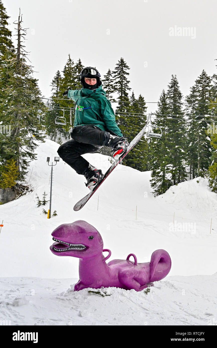 Junge macht Snowboarden springen über lila Dinosaurier am Mount Seymour Ski Hill, North British Columbia, Kanada Stockfoto