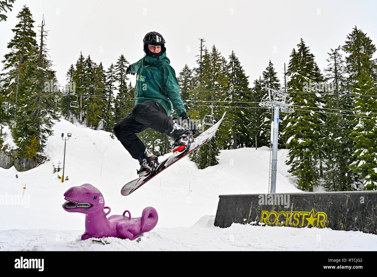 Junge macht Snowboarden springen über lila Dinosaurier am Mount Seymour Ski Hill, North British Columbia, Kanada Stockfoto