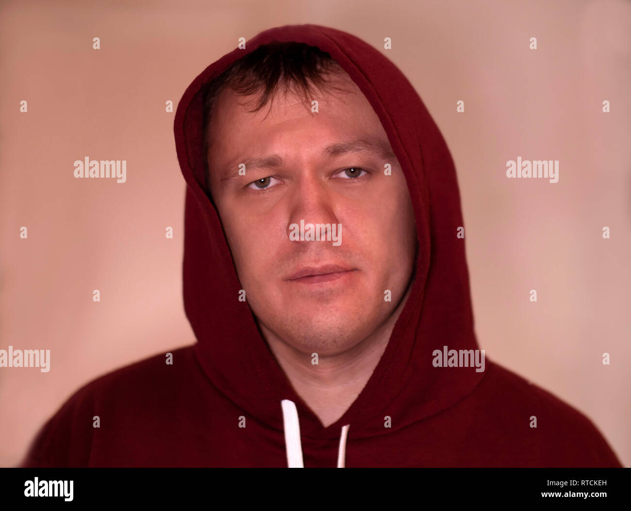 Porträt einer ernsthaften jungen Mann in eine Haube auf hellem Hintergrund, Blick in die Kamera, close-up Stockfoto