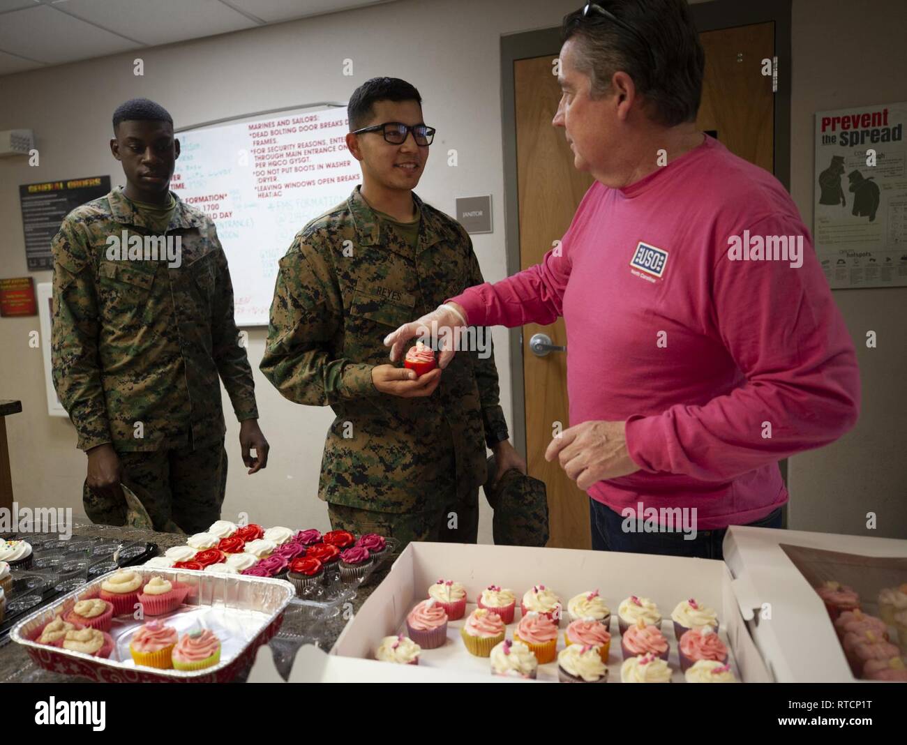Jeffrey T. Weller, einem Freiwilligen mit den Jacksonville, N.C., USA Service Organisationen (USO), Hände, die Cupcakes in US-Marines zu Financial Management Schule zugewiesen, Marine Corps Combat Service Support Schulen (MCCSSS) während der USO Cupcake Drop in Camp Johnson, N.C., 14.02.2019. Die Jacksonville, N.C., USO brachte eine süße Überraschung zu MCCSSS Studenten, die von der lieben am Valentinstag durch Backen und spenden Cupcakes für den Betrieb: Cupcake fallen. Stockfoto