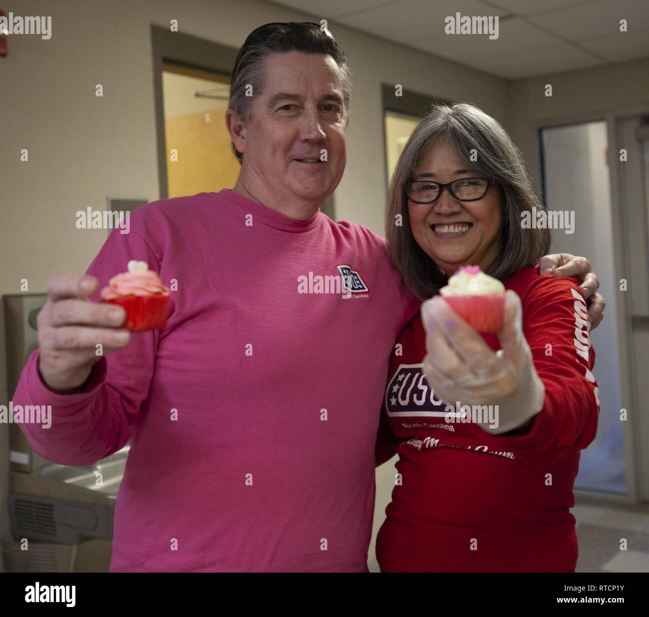 Jeffrey T. Weller, und Noriko Weller, Freiwillige mit den Jacksonville, N.C., USA Service Organisationen (USO), für ein Foto während der USO Cupcake Drop in Camp Johnson, N.C., Feb.14, 2019 darstellen. Die Jacksonville, N.C., USO brachte eine süße Überraschung zum Marine Corps Combat Service Support Schulen Studenten, die von der lieben am Valentinstag durch Backen und spenden Cupcakes für den Betrieb: Cupcake fallen. Stockfoto