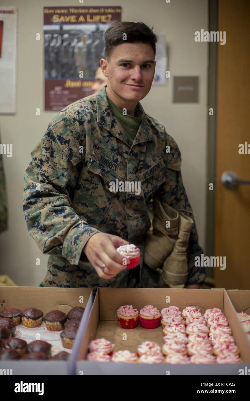 Us Marine Corps Pvt. Robert E. Torres, ein Student zugeordnet die Personaladministration Schule, Marine Corps Combat Service Support Schulen (MCCSSS), packt eine Cupcake während der United Service Organisationen" (USO) Cupcake Drop in Camp Johnson, N.C., 14.02.2019. Die Jacksonville, N.C., USO brachte eine süße Überraschung zu MCCSSS Studenten, die von der lieben am Valentinstag durch Backen und spenden Cupcakes für den Betrieb: Cupcake fallen. Stockfoto