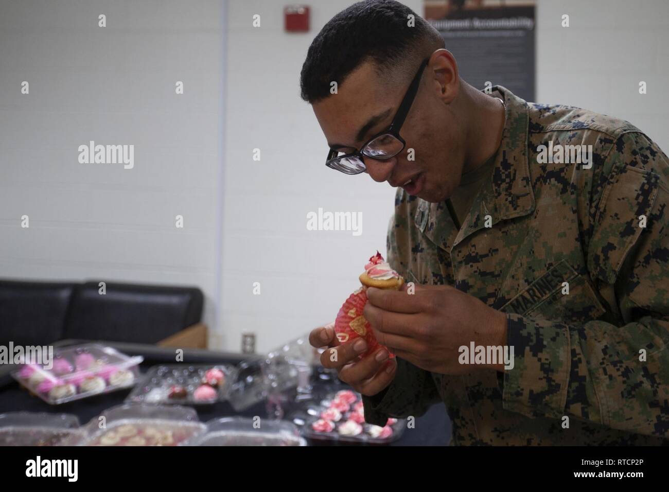 Us Marine Corps Pfc. Gabriel M. Thomas, ein Student zu Masse Schule, Marine Corps Combat Service Support Schulen (MCCSSS), un-wickelt eine Cupcake im Camp Johnson, N.C., 14.02.2019. Die Jacksonville, N.C., USA Service Organisationen brachte eine süße Überraschung zu MCCSSS Studenten, die von der lieben am Valentinstag durch Backen und spenden Cupcakes für den Betrieb: Cupcake fallen. Stockfoto