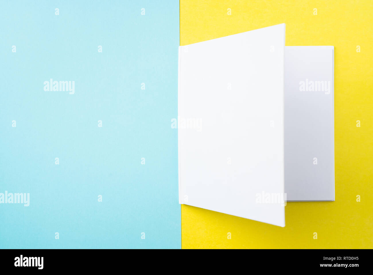 Designkonzept - Ansicht von oben öffnen Quadratische weiße Notebook auf bunten gelber und blauer Hintergrund für mockup Serie 4 Stockfoto