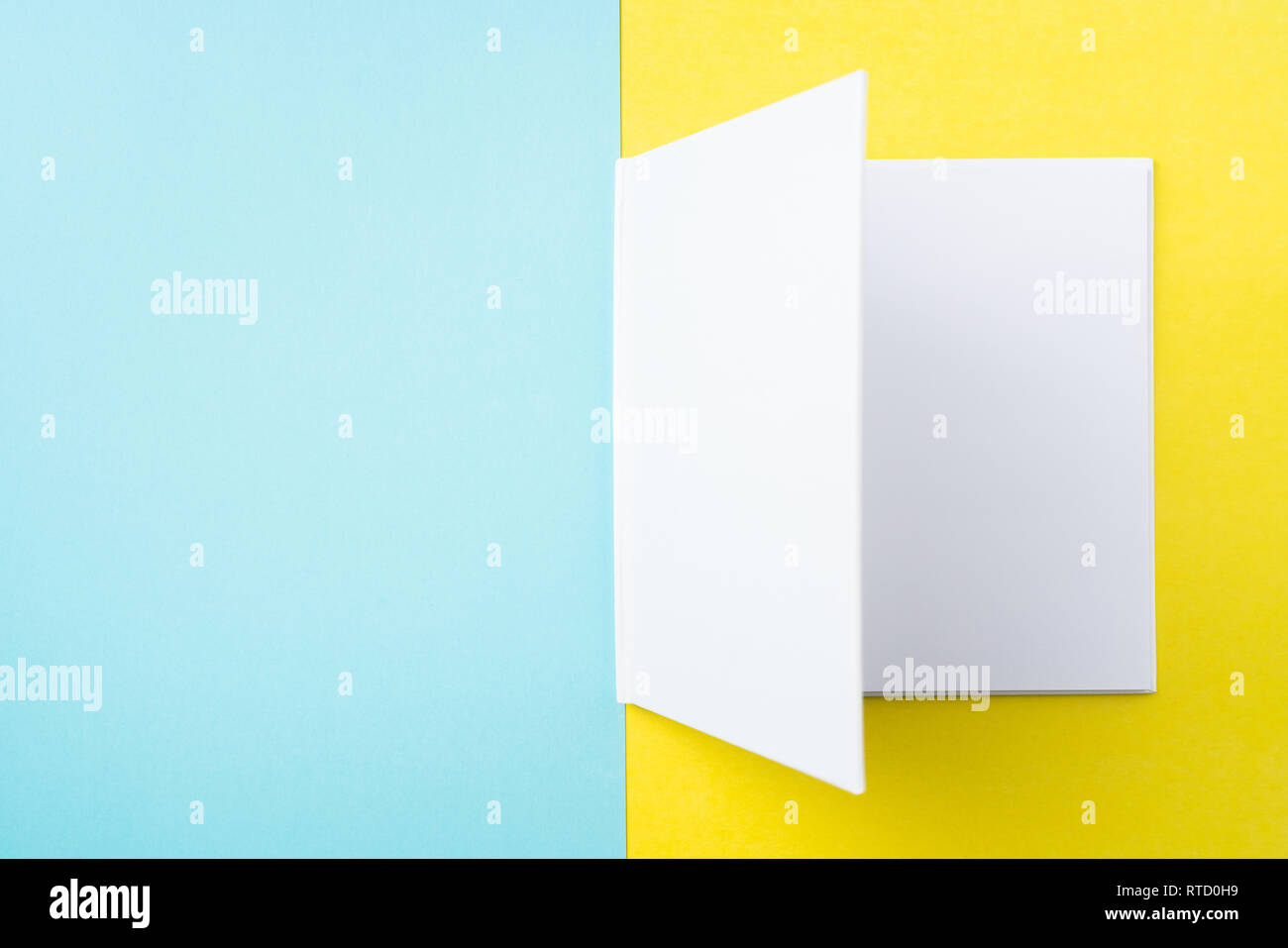 Designkonzept - Ansicht von oben öffnen Quadratische weiße Notebook auf bunten gelber und blauer Hintergrund für mockup Serie 5 Stockfoto