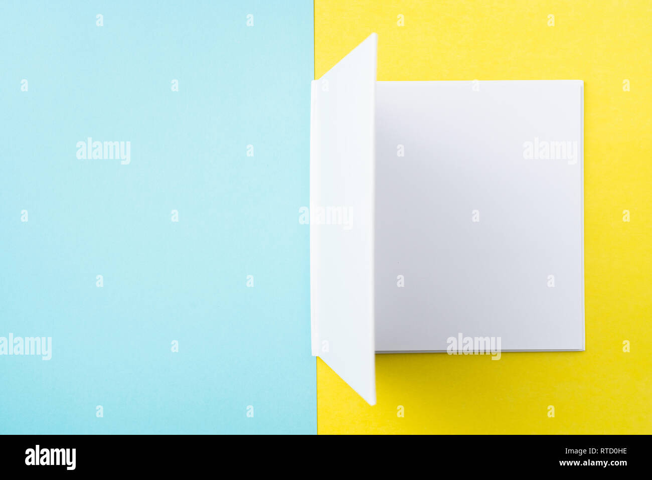 Designkonzept - Ansicht von oben öffnen Quadratische weiße Notebook auf bunten gelber und blauer Hintergrund für Modell der Serie 6 Stockfoto