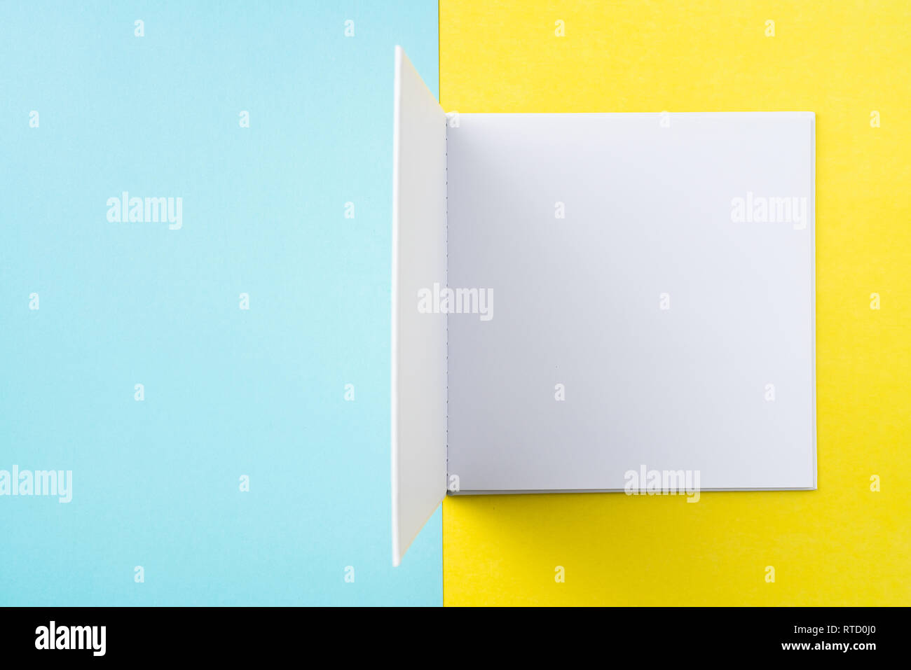 Designkonzept - Ansicht von oben öffnen Quadratische weiße Notebook auf bunten gelber und blauer Hintergrund für mockup Serie 8 Stockfoto