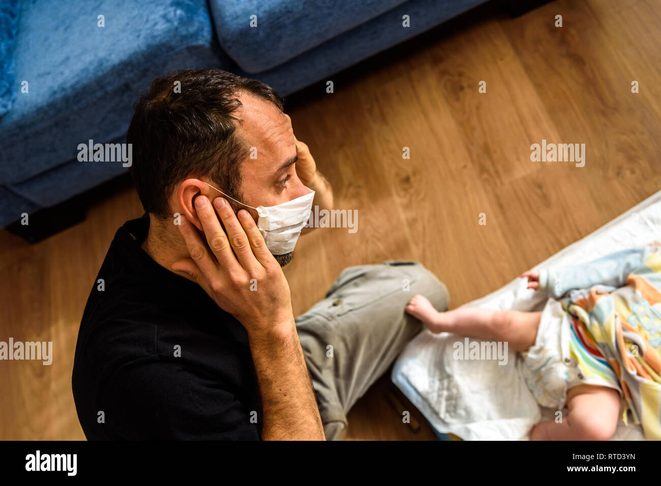 Anfänger Vater ändern Der stinkenden Windel eines Babys, das Tragen einer Maske für schlechte Gerüche mit einer Geste der Abscheu. Stockfoto