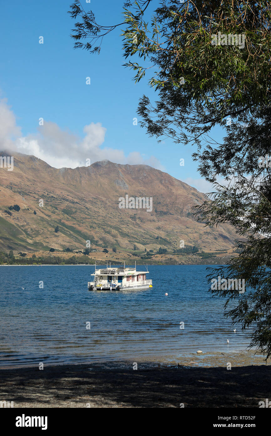 Hausboot an einem sonnigen Sommertag auf einem ruhigen See Wanaka, mit Bergen von Wanaka, Neuseeland Südinsel Stockfoto