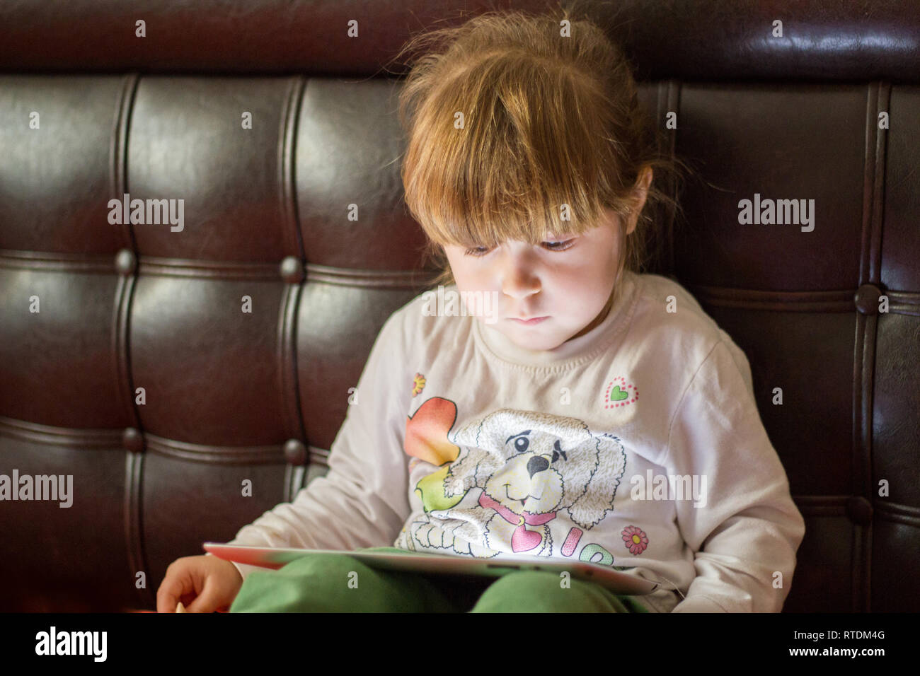 Kleines Mädchen Kind spielt mit tablet pc und schaut Stockfoto