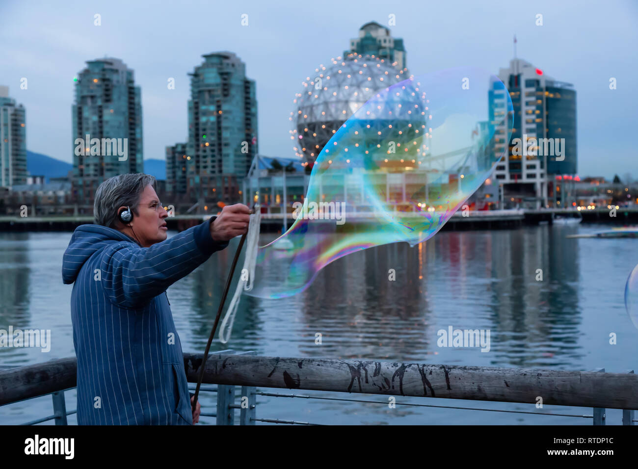 Downtown Vancouver, British Columbia, Kanada - 29 November 2018: Mann, der grosse Seifenblasen in False Creek während einer lebhaften Sonnenuntergang. Stockfoto